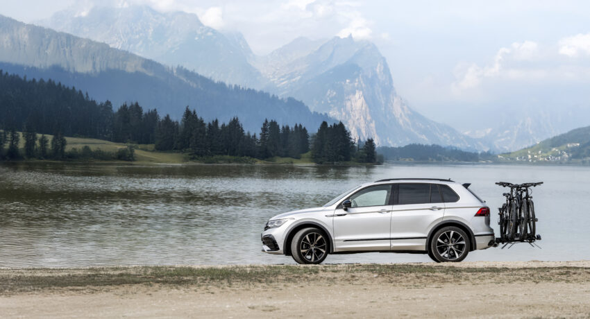 Auto mit Kupplungsträger und Fahrrädern vor See und Bergkulisse