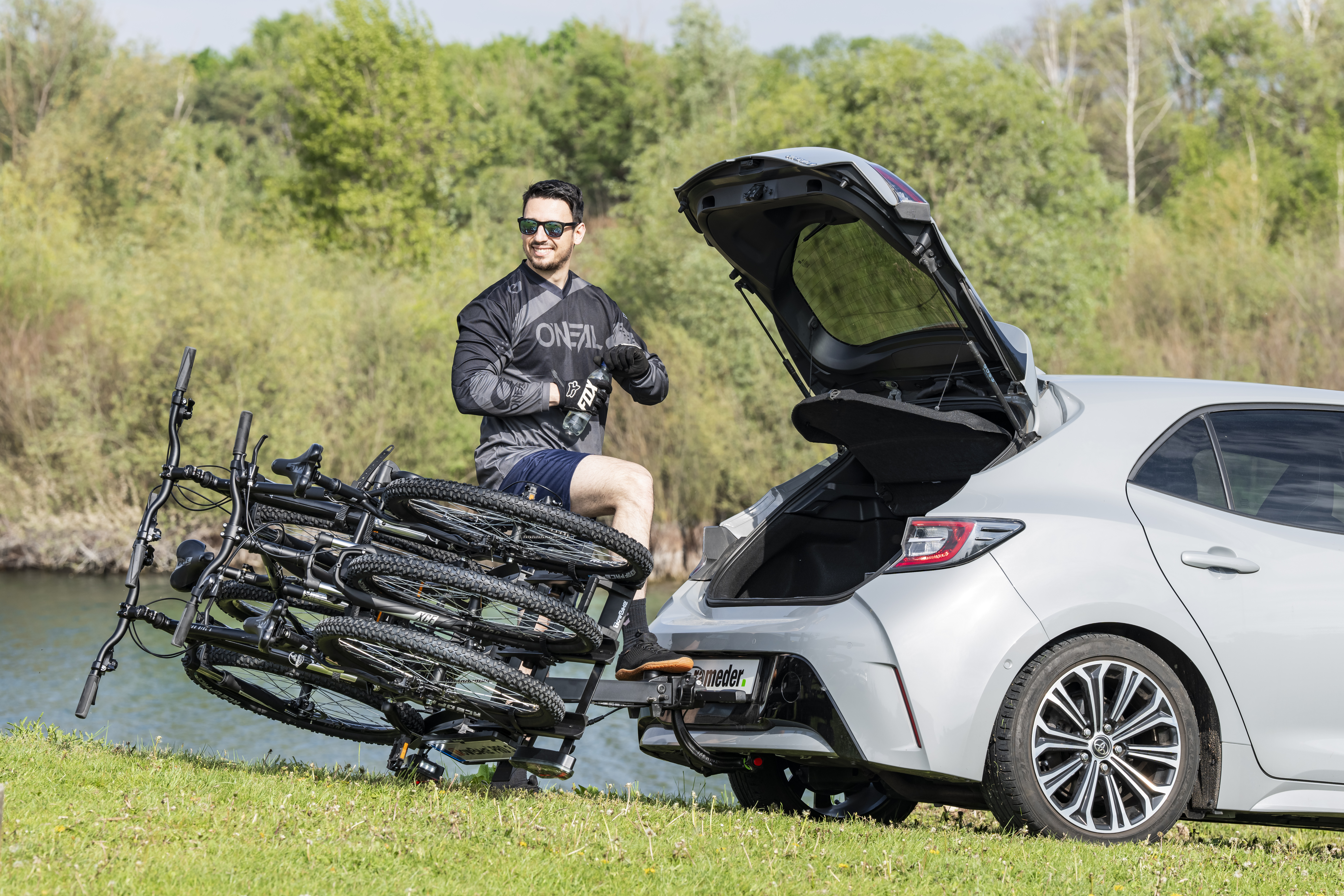 Heck eines grauen Autos mit montiertem TowBoke PRO 3, 3 geladenen Fahrrädern und geöffnetem Kofferraum
